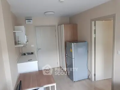 Compact modern kitchen with fridge and dining table in cozy apartment.