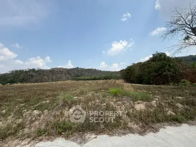 Expansive land plot with scenic mountain views under a clear blue sky, ideal for development.