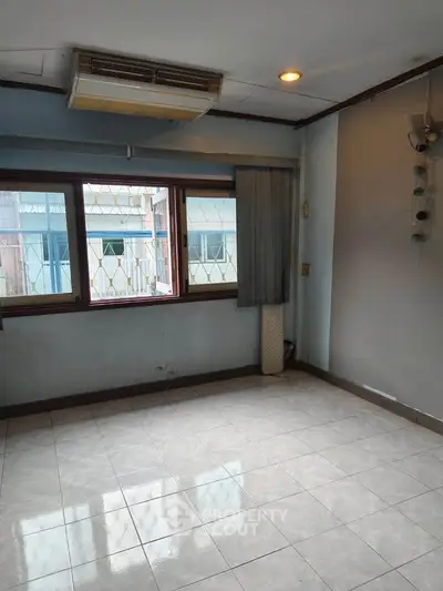 Spacious empty room with large windows and tiled flooring, ideal for customization.