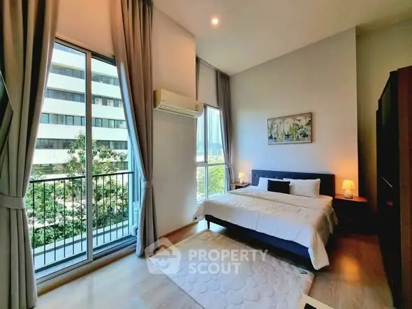 Bright and airy bedroom with large windows and modern decor in urban setting.