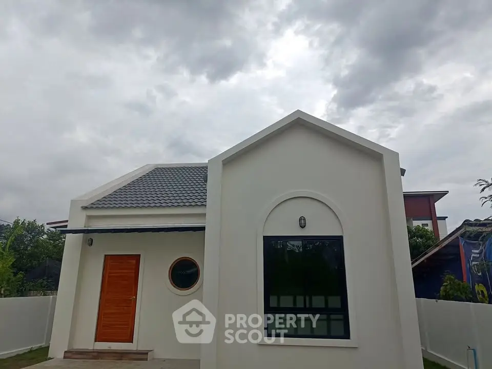 Charming modern house with unique architecture and wooden door under a cloudy sky.
