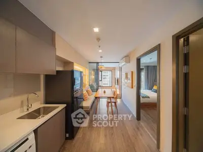 Modern open-plan apartment with sleek kitchen and cozy living area, featuring stylish decor and natural light.