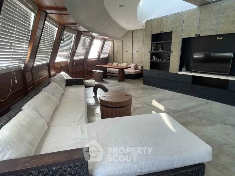 Spacious modern living room with unique angled windows and stylish furniture.