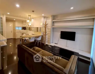 Modern living room with open kitchen, stylish lighting, and sleek furniture.