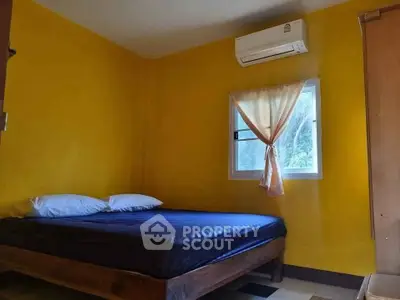 Cozy bedroom with vibrant yellow walls and air conditioning, perfect for relaxation.