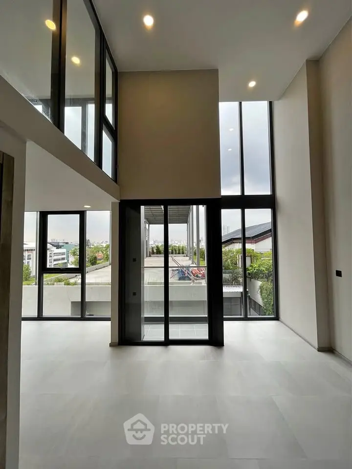 Spacious modern living room with floor-to-ceiling windows and balcony access
