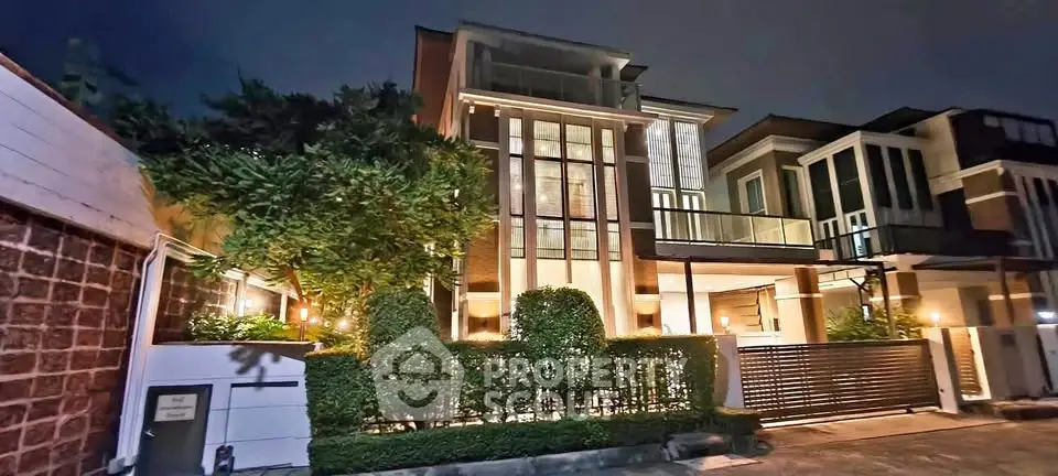 Luxurious modern house exterior with elegant lighting and lush greenery at night.