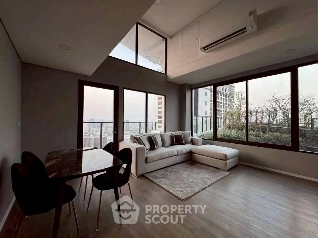 Modern living room with large windows and city view, featuring a cozy sofa and dining area.