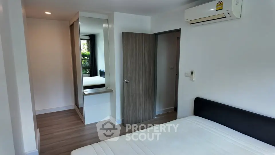 Modern bedroom with sleek design, featuring built-in wardrobe and air conditioning.