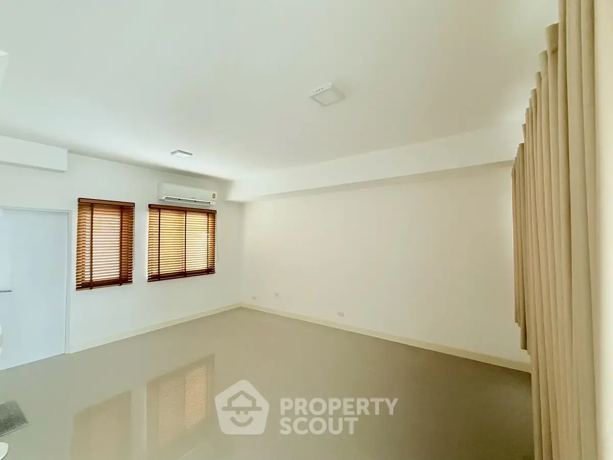 Spacious empty room with tiled floor and large windows, ideal for customization.