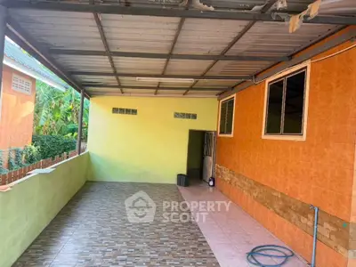 Spacious covered outdoor patio with tiled flooring and vibrant wall colors.