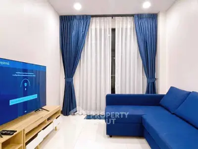 Modern living room with blue sofa and curtains, featuring a sleek TV setup.