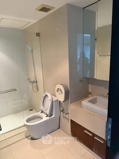 Modern bathroom with sleek fixtures and glass shower enclosure in a contemporary apartment.
