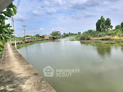 Scenic riverside view with lush greenery and distant houses, perfect for tranquil living.