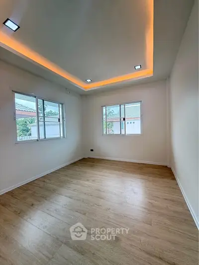 Spacious room with wooden flooring and modern recessed lighting, ideal for versatile living space.