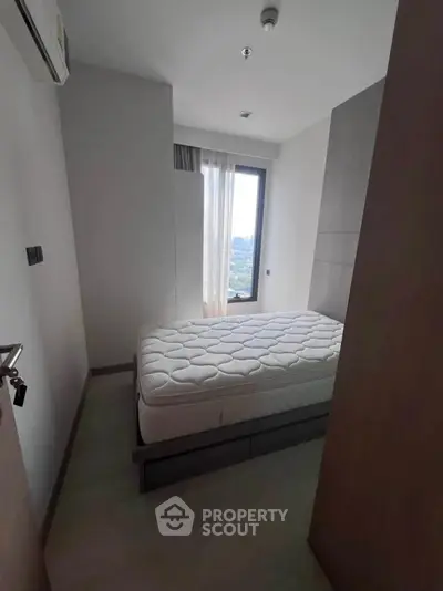 Cozy bedroom with a large window offering a stunning city view, perfect for relaxation.