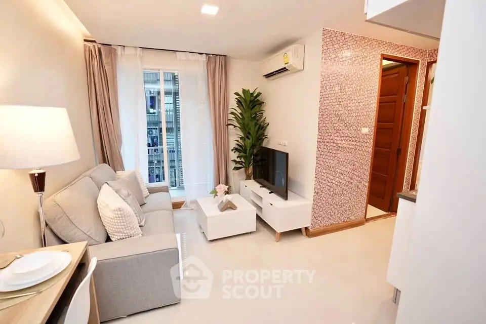 Modern living room with cozy sofa, TV, and stylish decor in a bright apartment.