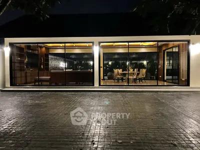 Luxurious modern living room with floor-to-ceiling windows and elegant dining area at night.