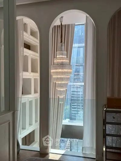 Luxurious interior with elegant chandelier and floor-to-ceiling windows offering stunning city views.