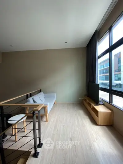 Modern loft-style living room with large windows and sleek furnishings