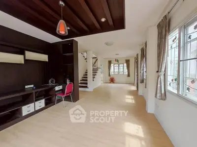 Spacious open-plan living area with wooden ceiling and ample natural light.