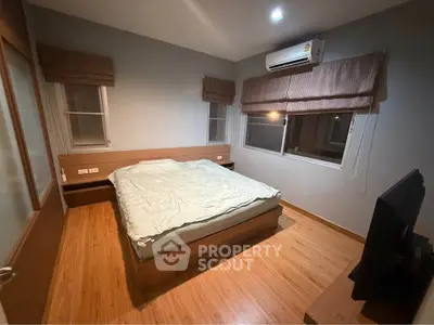 Cozy bedroom with wooden flooring, modern air conditioning, and ambient lighting for a comfortable living experience.