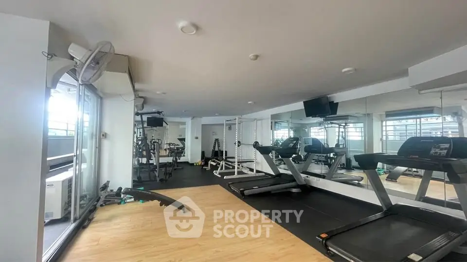 Modern gym with state-of-the-art equipment and spacious layout in luxury apartment building.