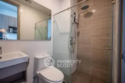 Modern bathroom with glass shower and sleek fixtures in contemporary apartment.