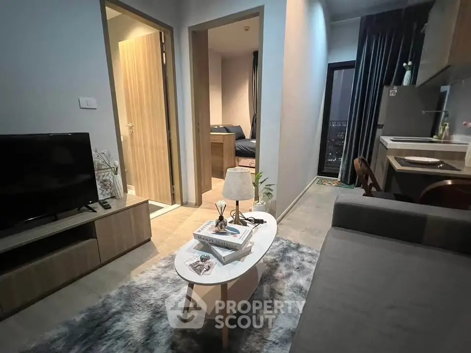Modern living room with cozy decor and open kitchen layout in a stylish apartment.