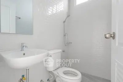 Modern minimalist bathroom with white tiles and sleek fixtures.