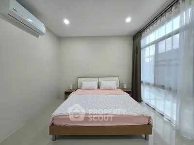 Spacious bedroom with modern decor and large windows for natural light