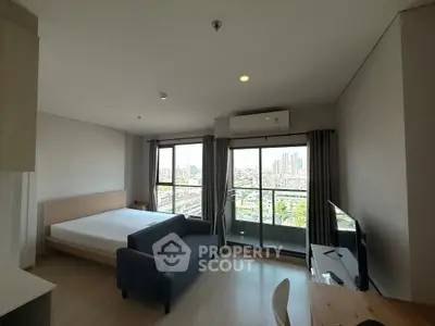 Modern studio apartment with city view, featuring a cozy living area and large windows for natural light.