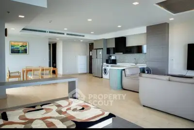 Spacious modern living room with open kitchen and dining area, featuring sleek appliances and stylish decor.