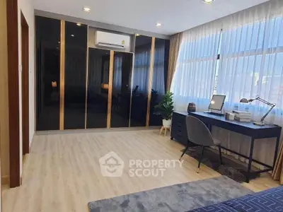 Spacious modern bedroom with large windows and sleek black wardrobe