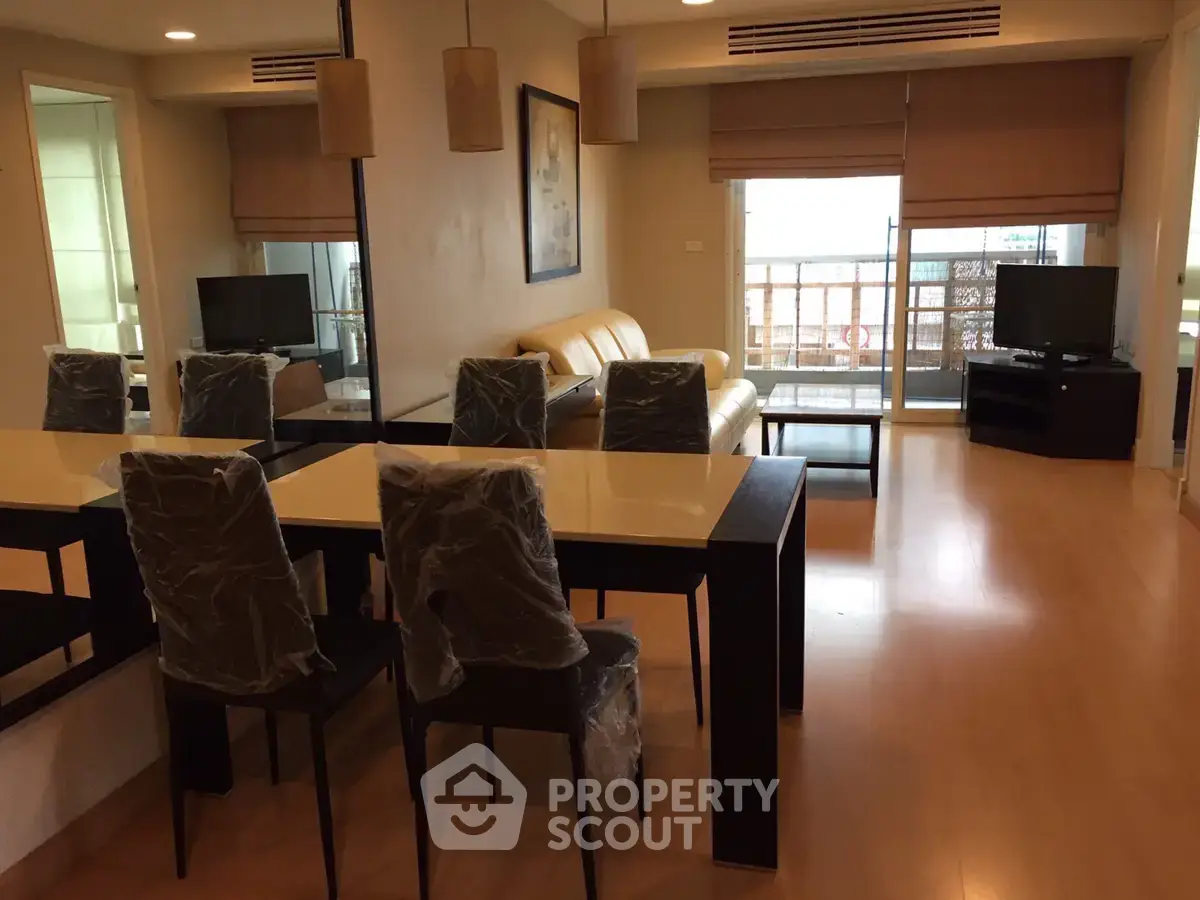 Spacious modern living room with dining area and balcony access, featuring sleek furniture and natural light.