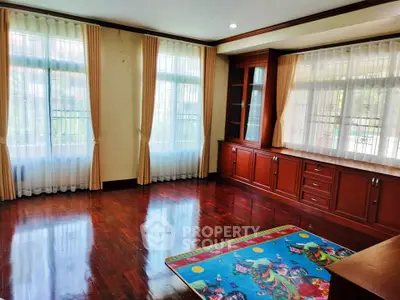 Spacious living room with polished wooden floors and large windows for natural light.