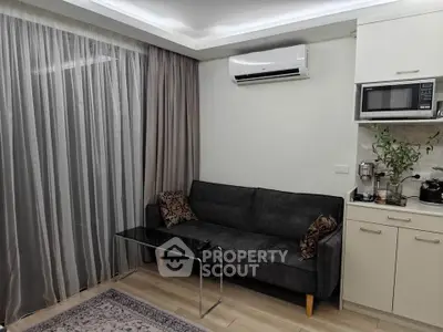 Modern living room with sleek sofa, air conditioning, and kitchenette featuring microwave and coffee maker.