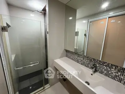 Modern bathroom with glass shower and sleek vanity in contemporary apartment.