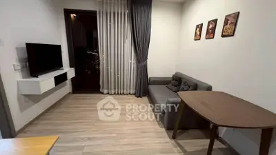 Cozy living room with modern decor, featuring a sleek sofa, wall-mounted TV, and elegant wooden table.