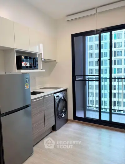 Modern kitchen with appliances and balcony view in a high-rise apartment