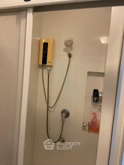 Compact bathroom shower area with modern fixtures and built-in shelf.