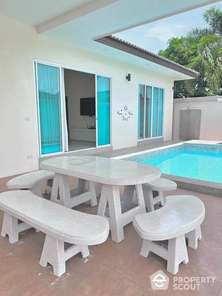 Charming poolside patio with modern outdoor furniture and sliding glass doors leading to a stylish interior.