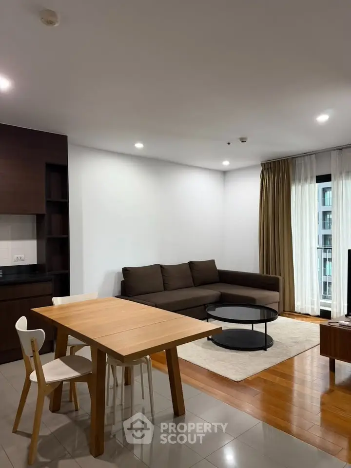 Modern living room with sleek furniture and open layout, featuring a cozy brown sofa and stylish dining area.