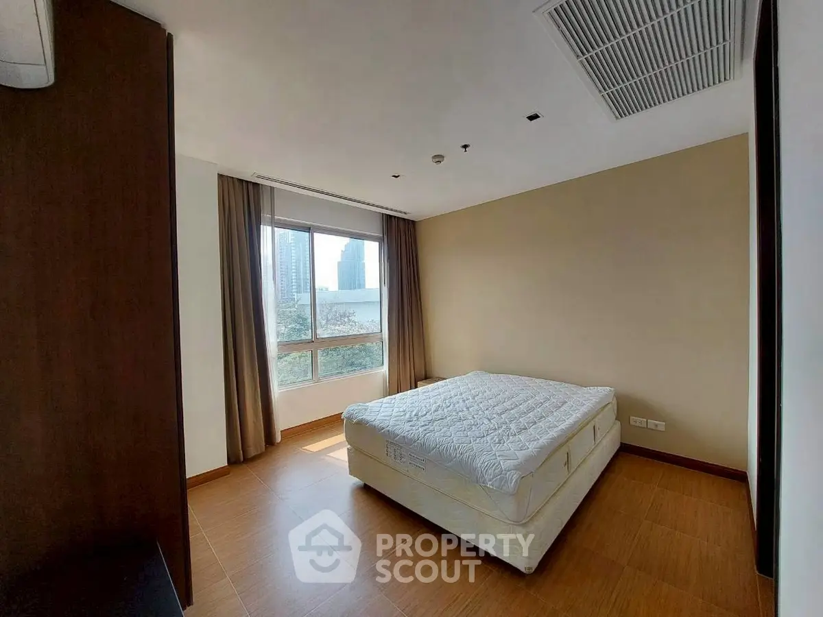 Spacious bedroom with large window and city view, featuring a comfortable bed and modern design.