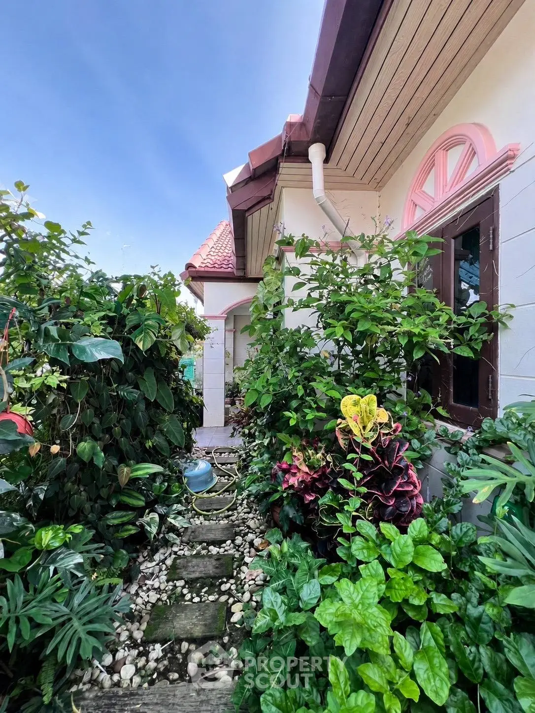Charming garden pathway leading to a picturesque house with lush greenery and vibrant flowers.