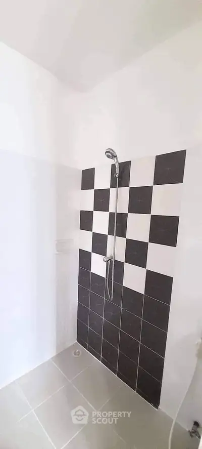 Modern bathroom with stylish black and white checkered tiles and sleek shower design.