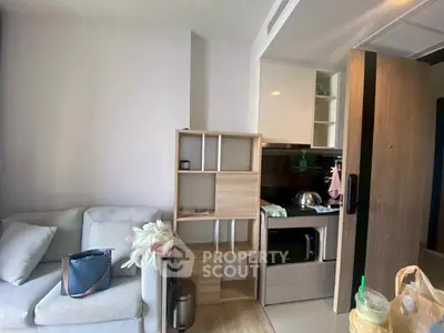 Modern compact living room with integrated kitchen area, featuring cozy sofa and stylish shelving unit.