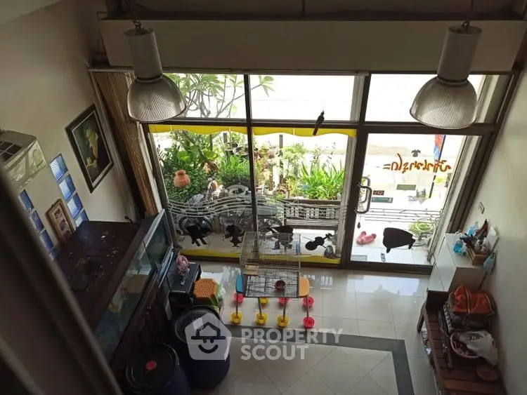 Charming living room with large windows and garden view, perfect for relaxation and natural light.