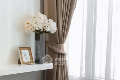 Elegant interior with beige curtains and floral decor on a white shelf, creating a cozy ambiance.