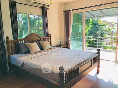 Spacious bedroom with large windows and balcony access, offering abundant natural light and serene views.